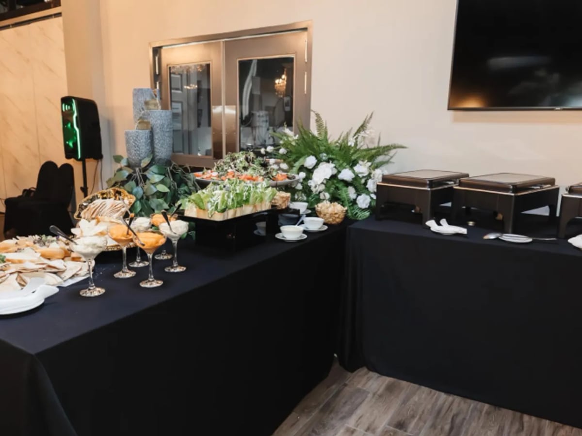 An elegant catering display with parfaits and canapés on black linen
